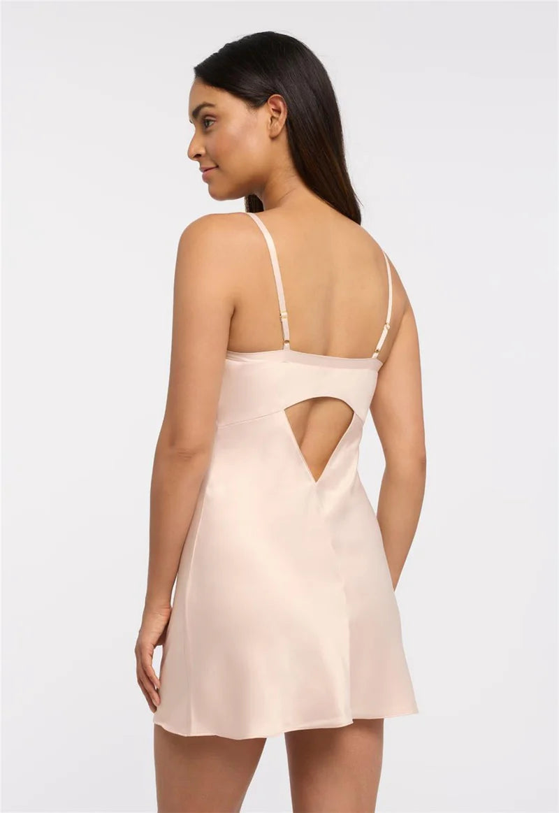 Woman wearing a beige slip dress with cut-out design on a white background