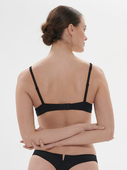 Woman wearing a black bra and underwear set on a white background
