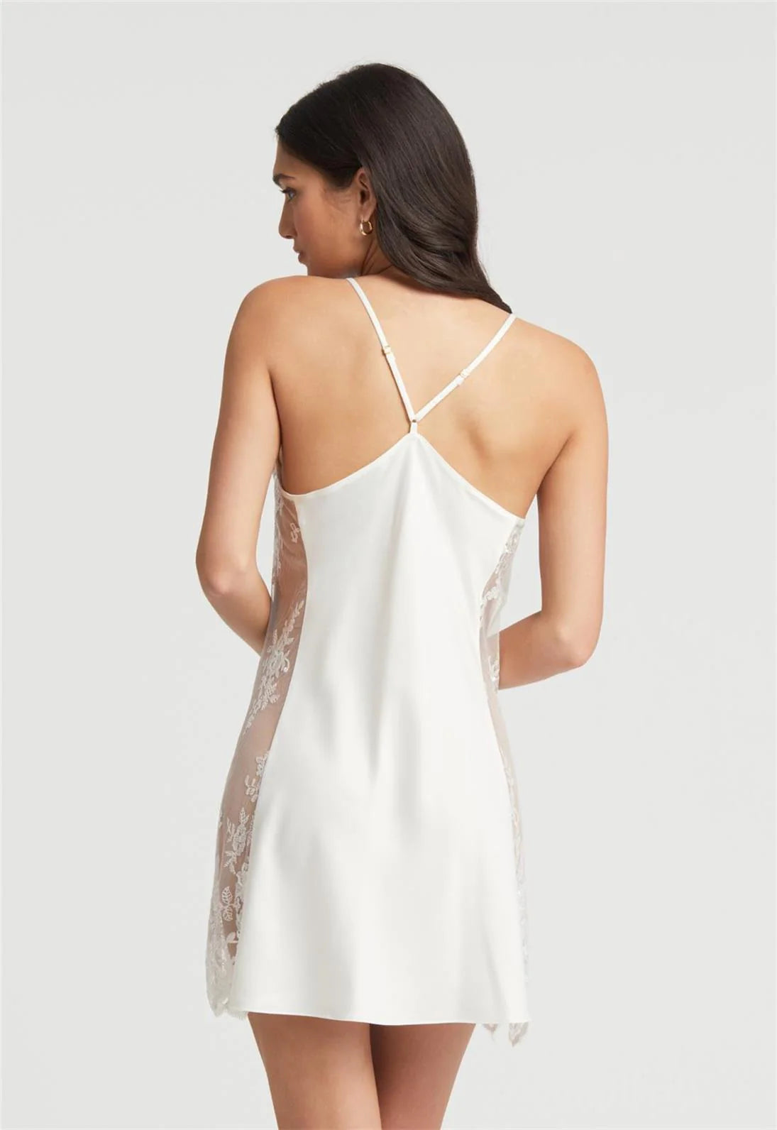 Woman wearing a white lace-trimmed nightgown against a plain background