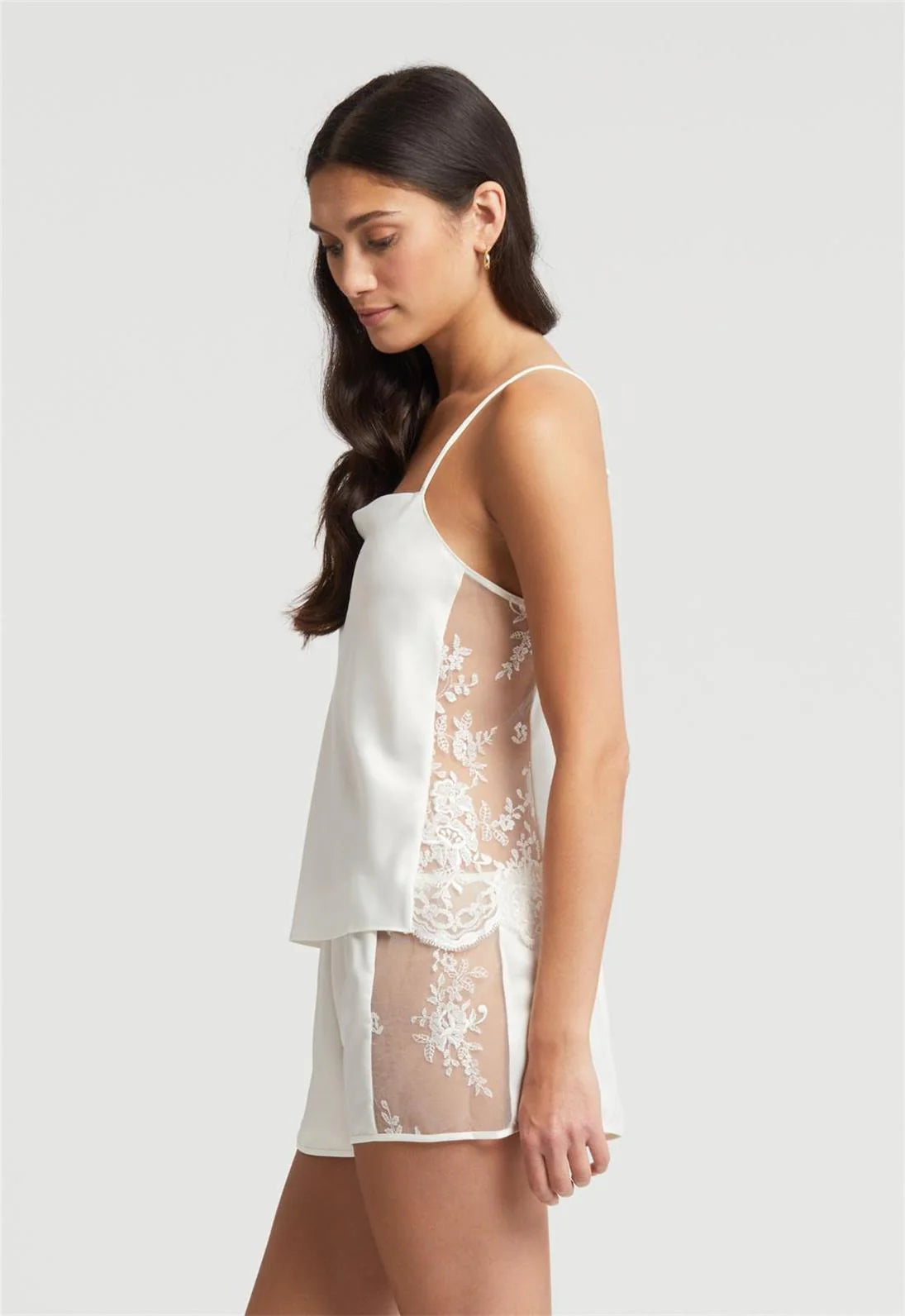 Woman wearing a white lace nightgown against a plain background