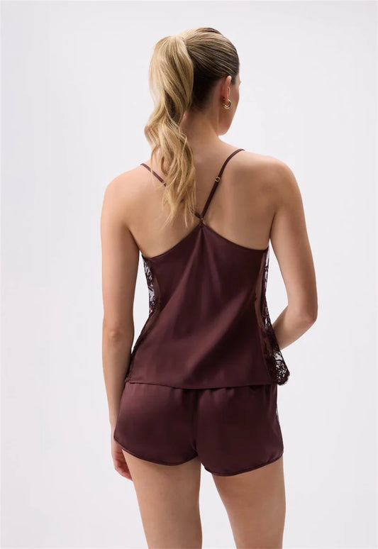 Woman wearing a burgundy satin nightgown with lace trim on a white background