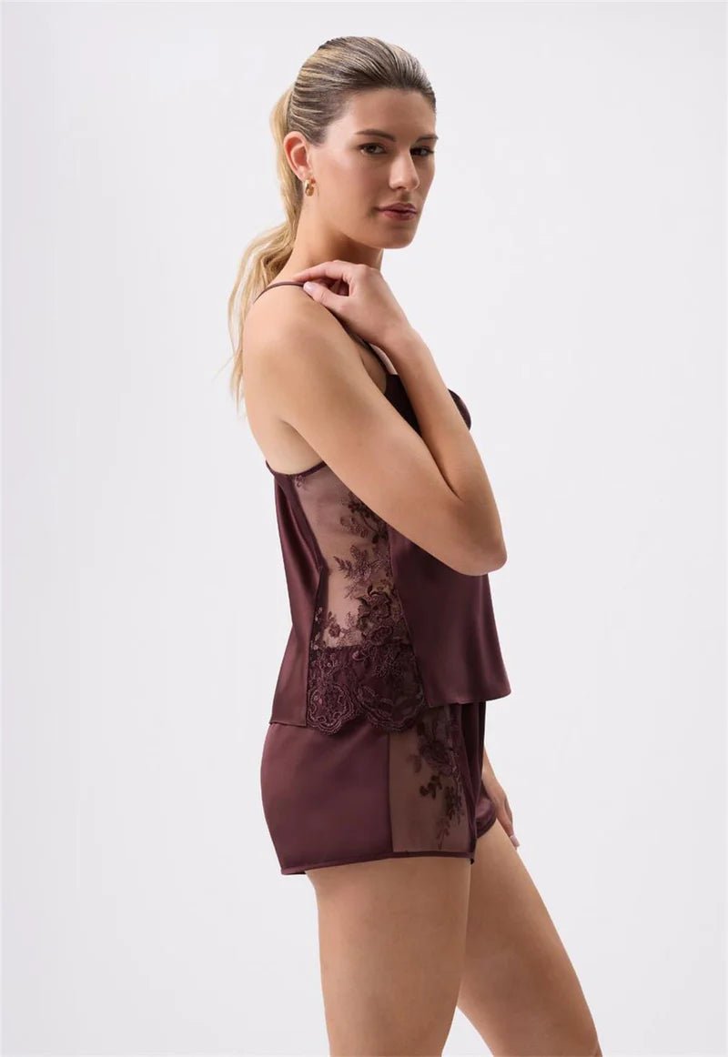 Woman wearing a burgundy lace nightgown against a white background