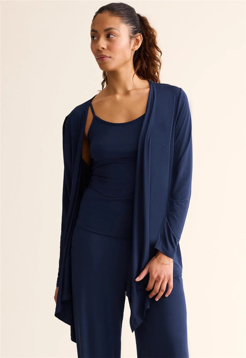 Woman wearing a navy blue outfit with a matching cardigan on a beige background