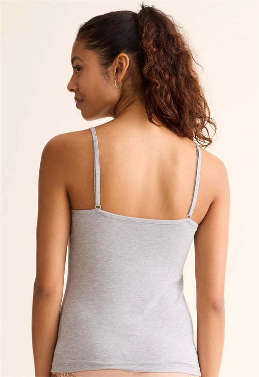 Woman wearing a gray tank top with thin straps on a beige background