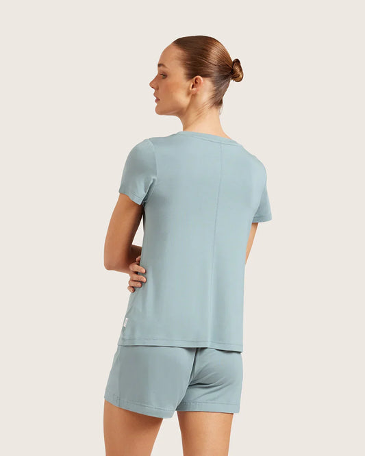 Woman wearing a light blue t-shirt and shorts set on a beige background