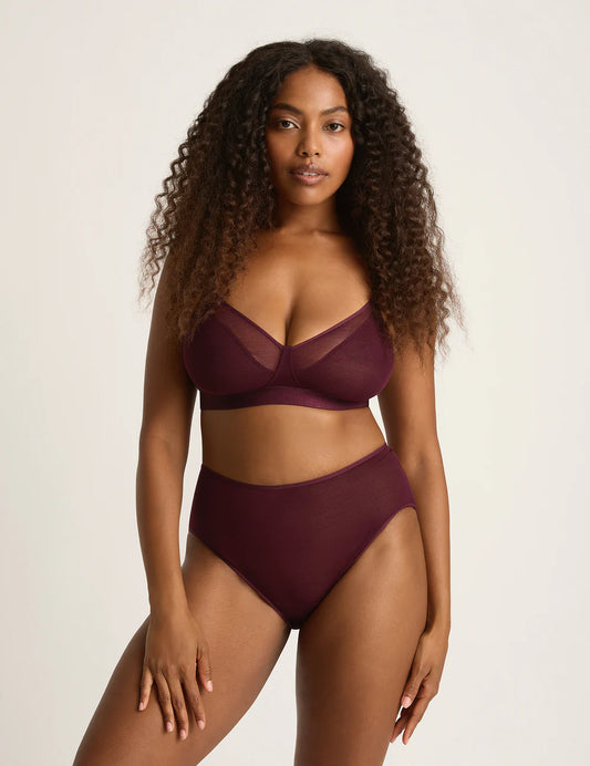 Woman wearing a burgundy bikini set against a plain background