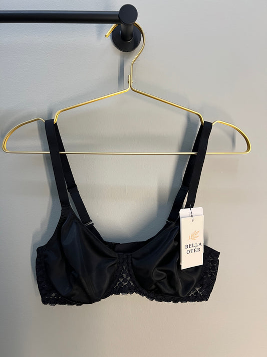 Black bra on a gold hanger with a visible brand tag against a gray background