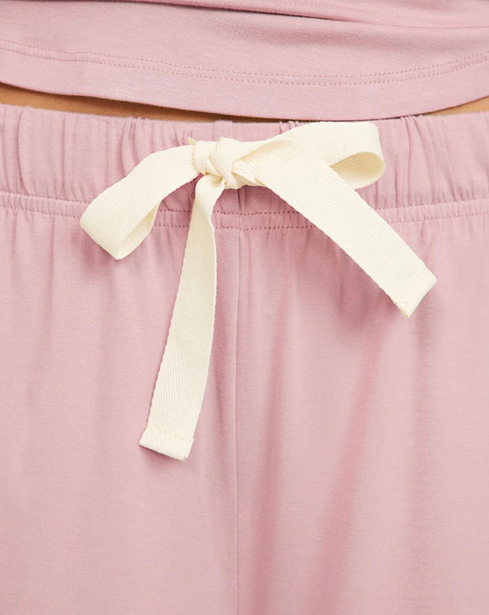 Pink garment with a white ribbon tie on a matching pink background