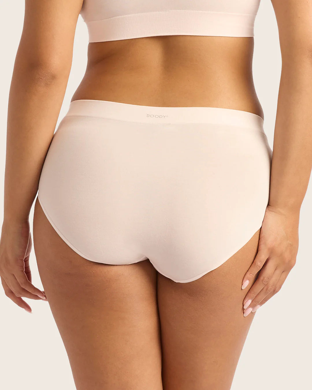 Beige high-waisted underwear worn by a person on a plain background