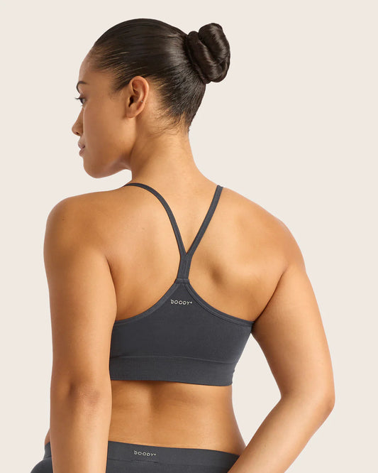 Woman wearing a gray sports bra with 'Body' branding on a light pink background