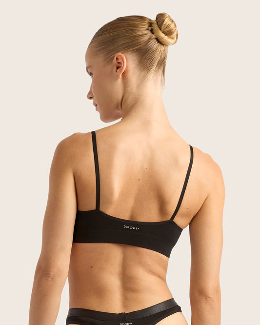 Woman wearing a black sports bra and underwear set on a light background