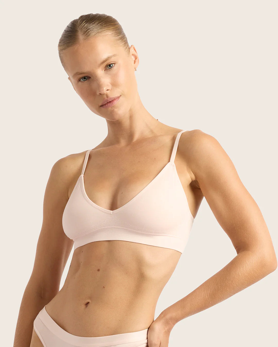 Woman wearing a beige bra and underwear set on a plain background