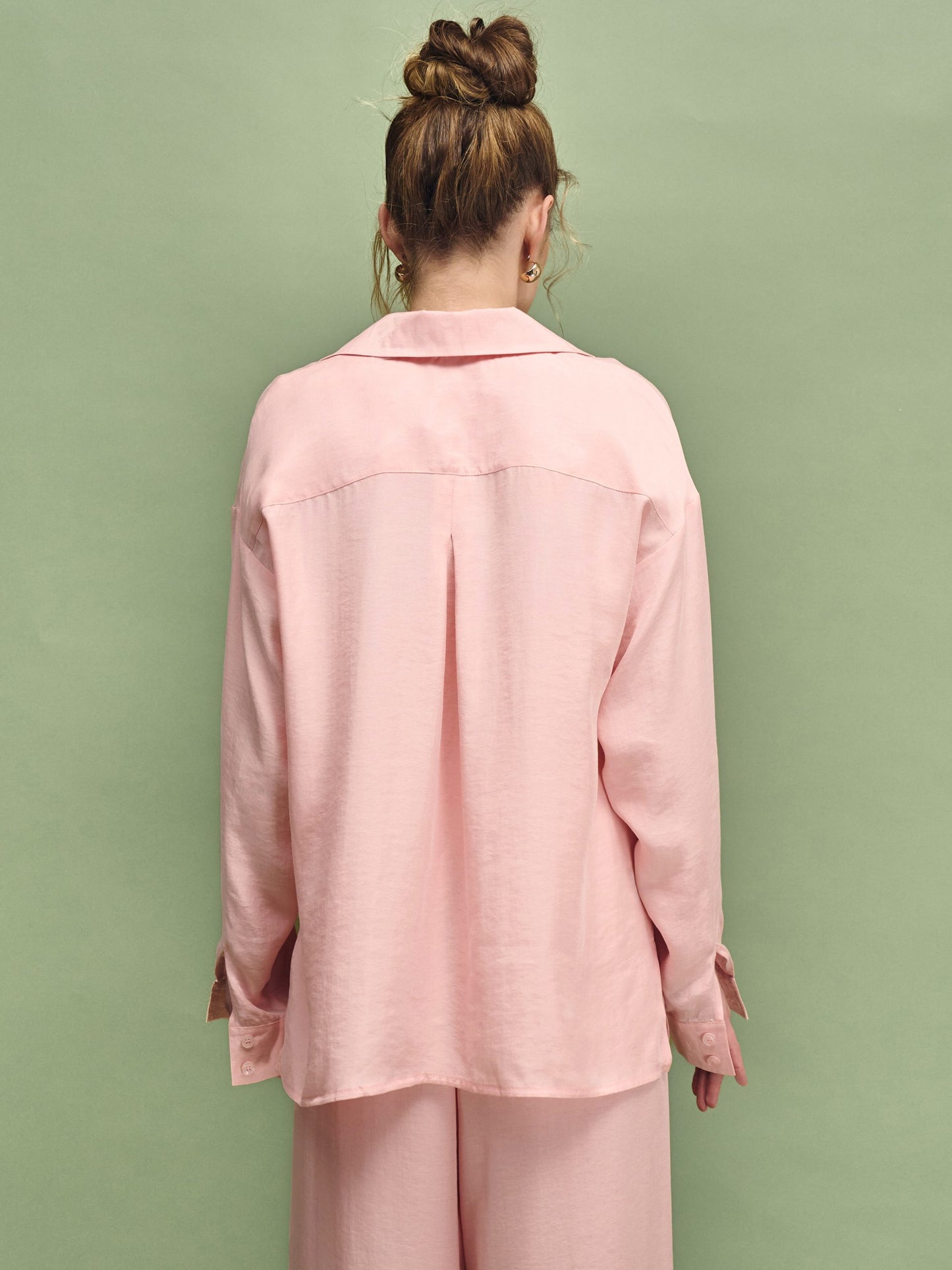 Person wearing a pink outfit against a green background