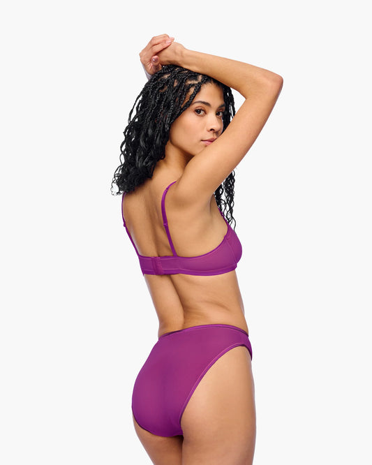 Woman wearing a purple bikini against a white background