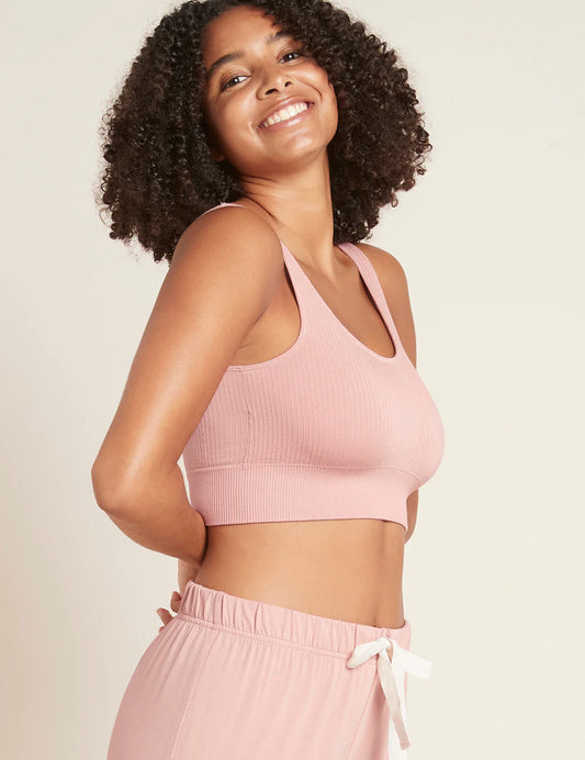 Woman wearing a pink sports bra and shorts set against a plain background