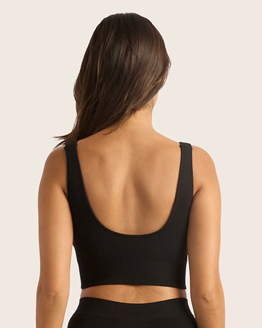 Person wearing a black sports bra on a plain background