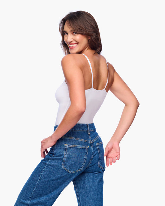 Woman wearing a white tank top and blue jeans on a white background