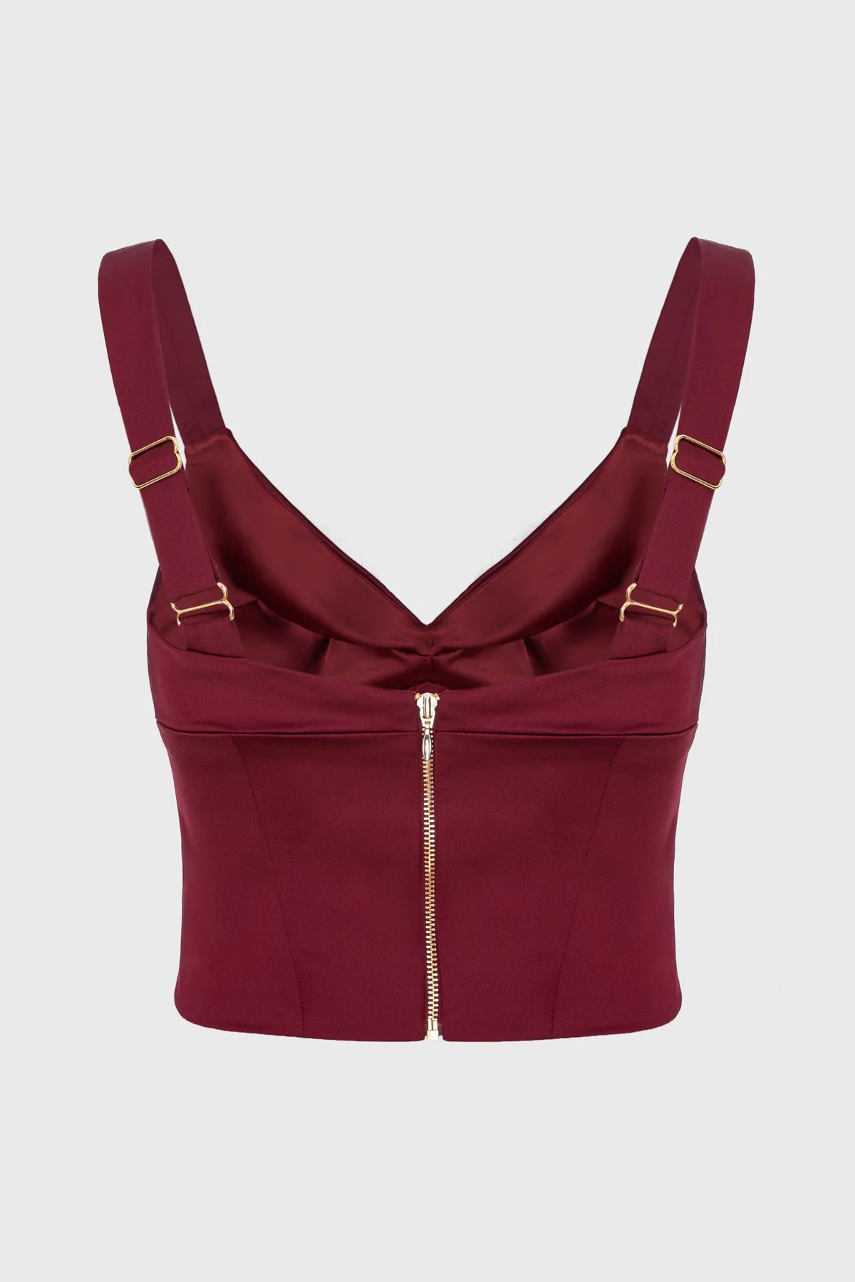 Maroon corset top with gold straps and zipper on a light gray background