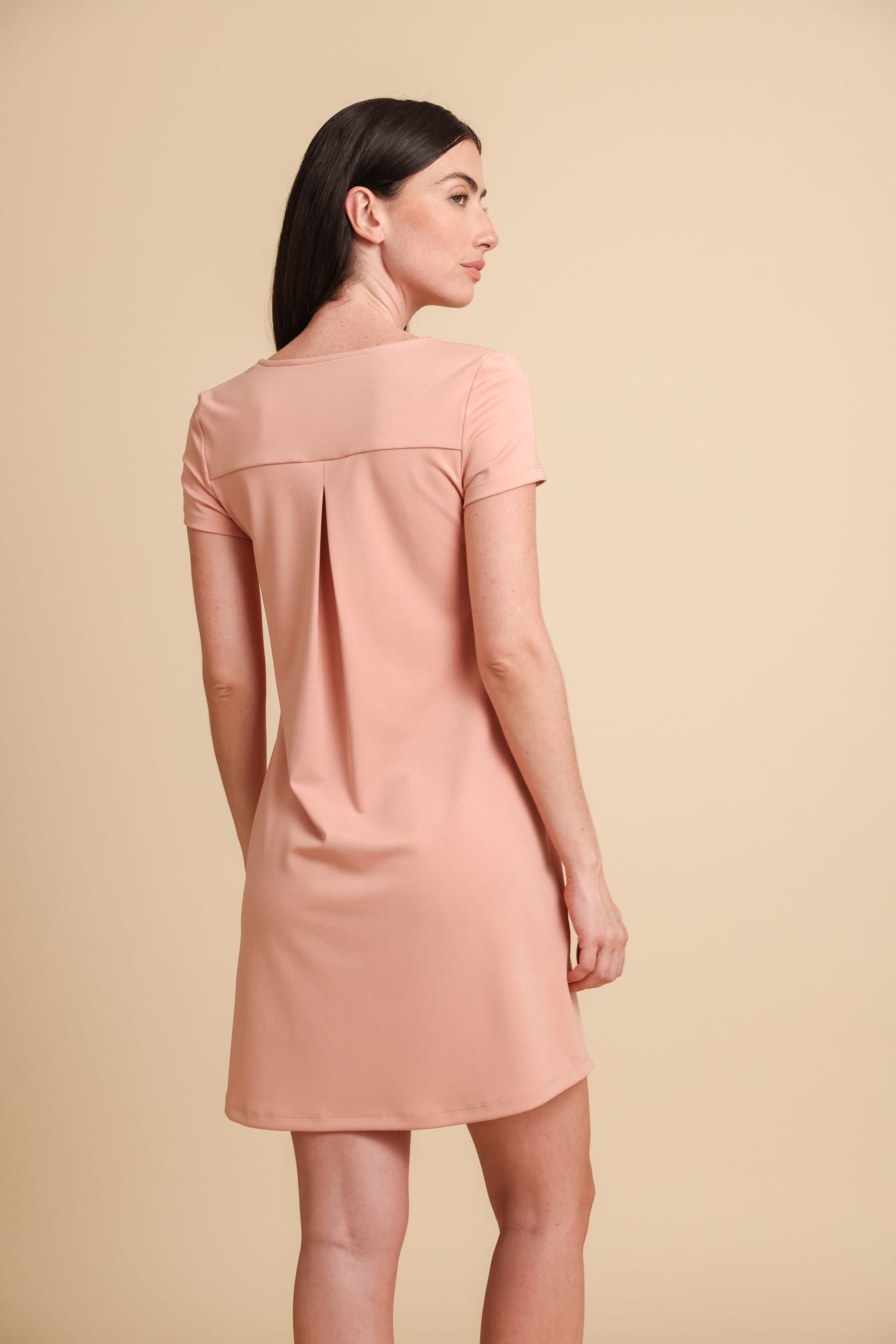 Woman wearing a light pink dress against a beige background