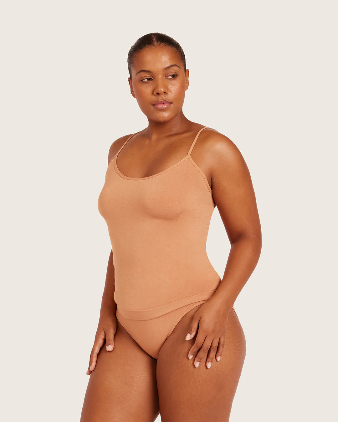 Woman wearing a beige swimsuit against a plain background