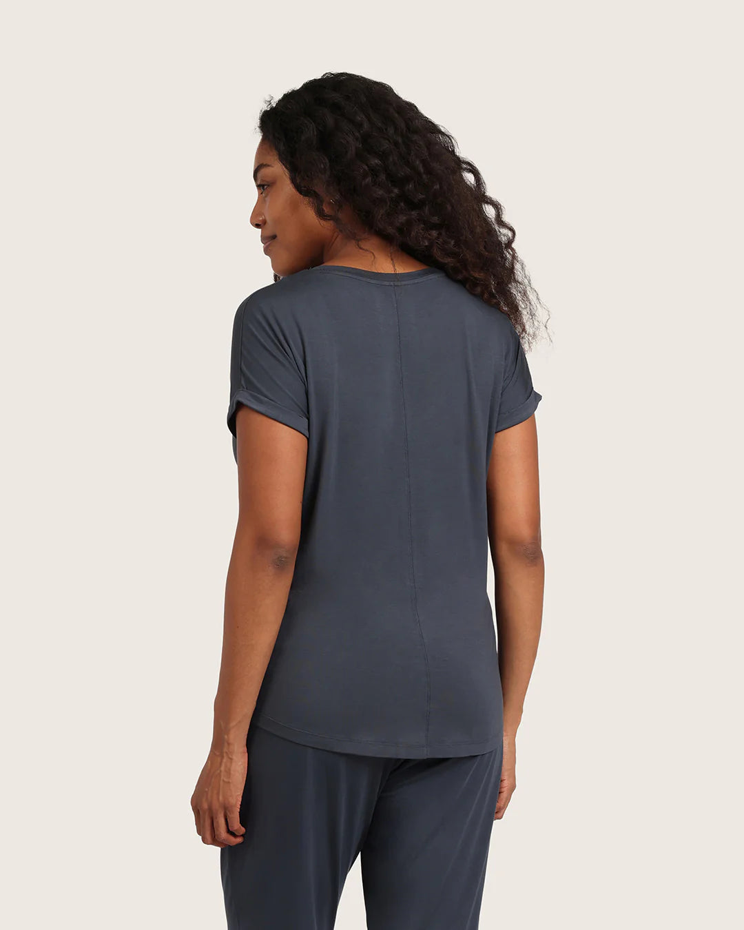 Woman wearing a dark gray t-shirt and pants on a beige background