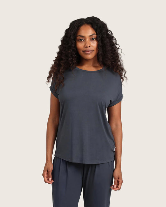 Woman wearing a dark gray t-shirt and pants on a beige background