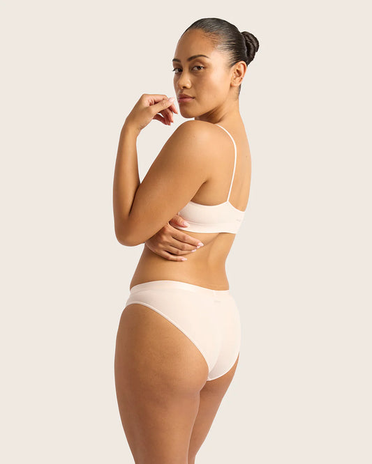Woman wearing a beige bra and underwear set on a plain background