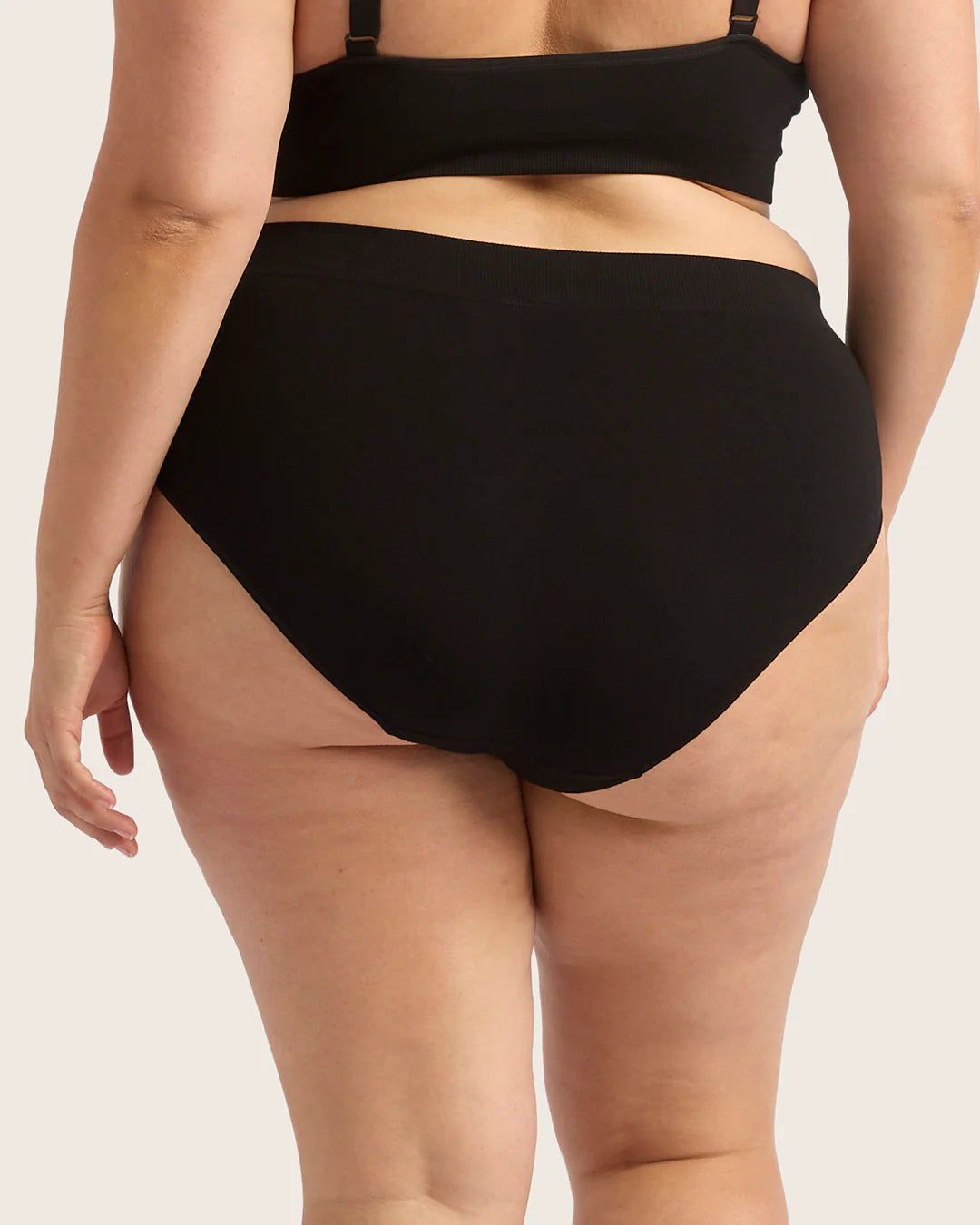 Person wearing a black bikini set on a plain background