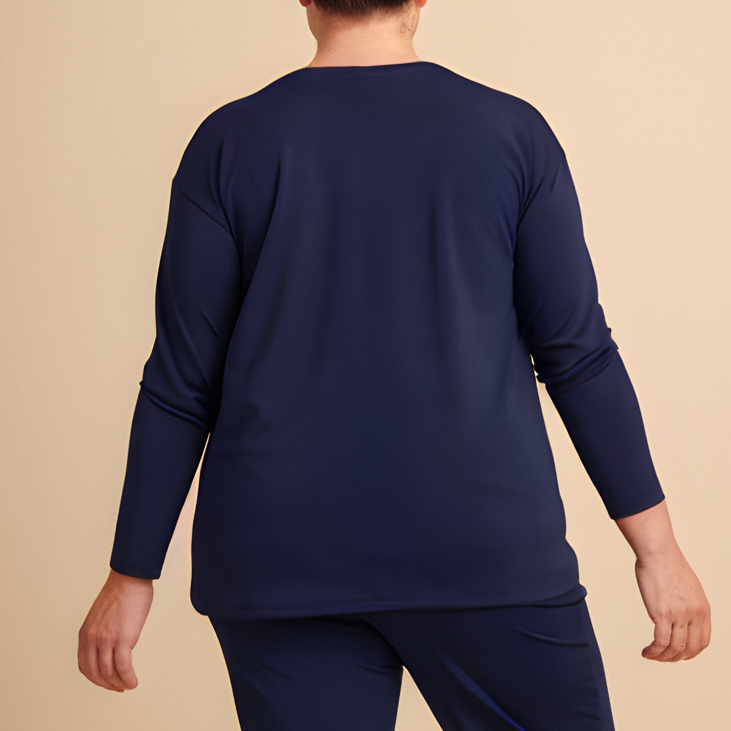 Person wearing a navy blue long-sleeve shirt and pants on a beige background