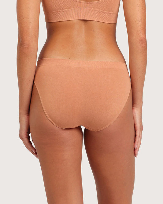 Person wearing a peach-colored athletic bra and underwear set on a light gray background