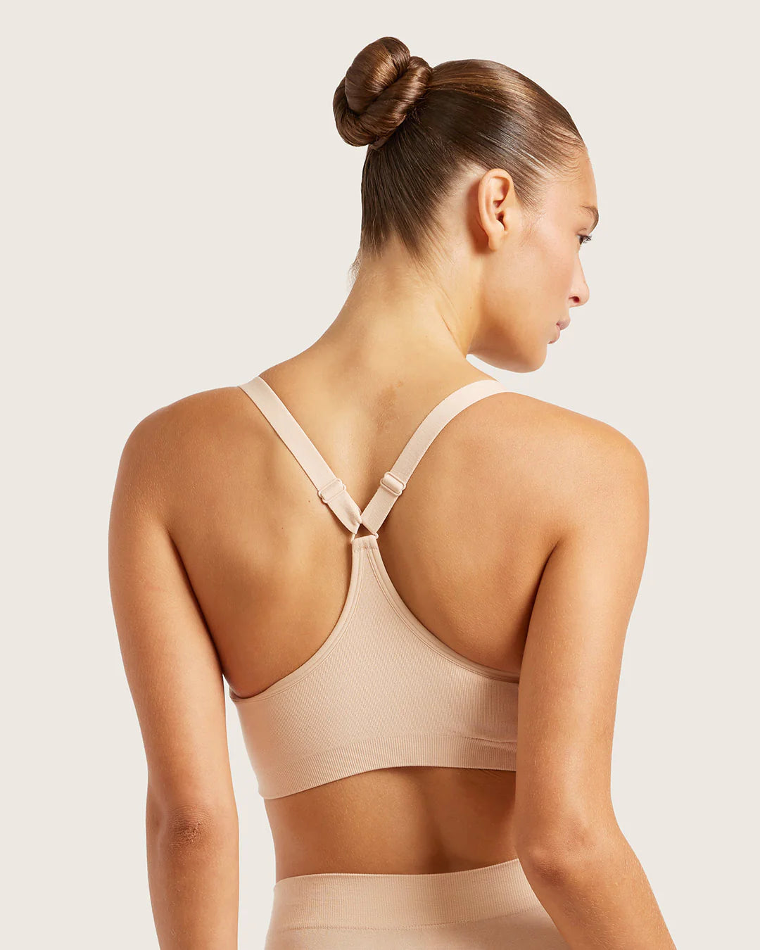 Woman wearing a beige sports bra against a light background