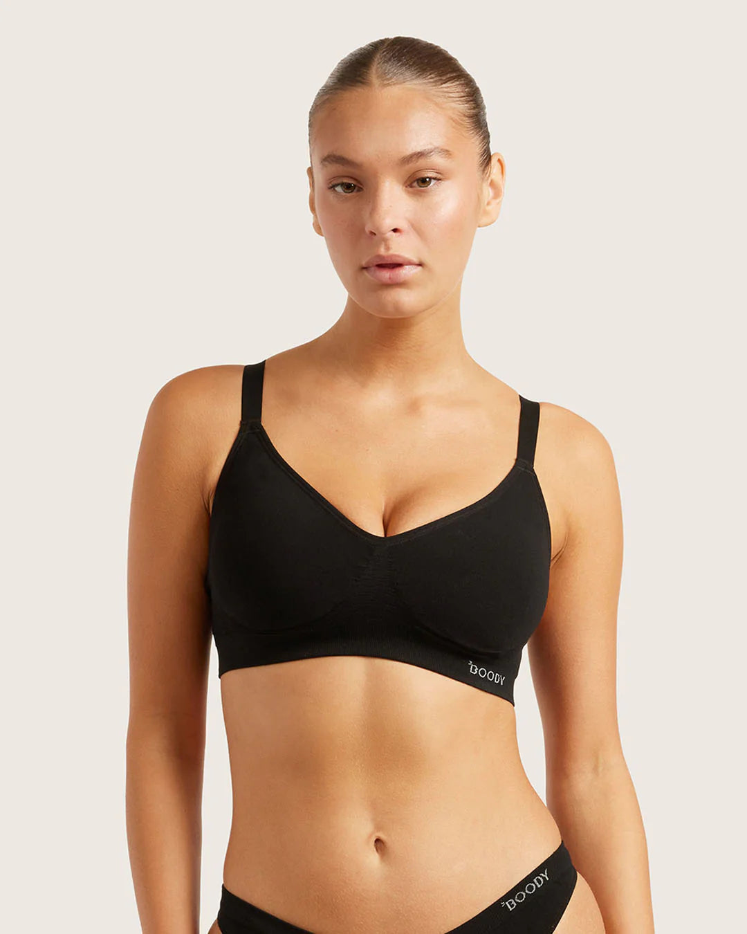 Woman wearing a black sports bra with 'Bodys' branding on a light background