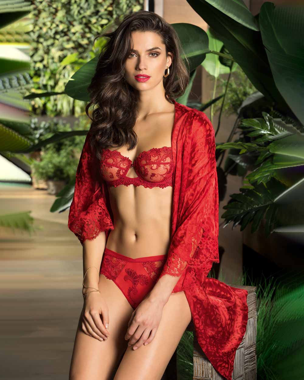 Woman wearing a red Lise Charmel lingerie set with a matching robe.