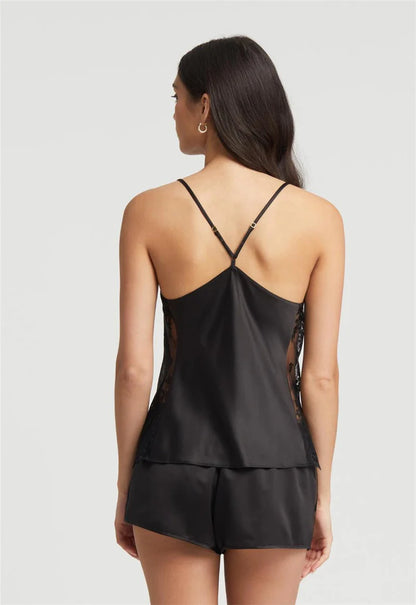 Woman wearing a black satin nightgown with lace details on a light gray background