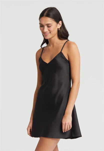 Woman wearing a black slip dress against a plain background