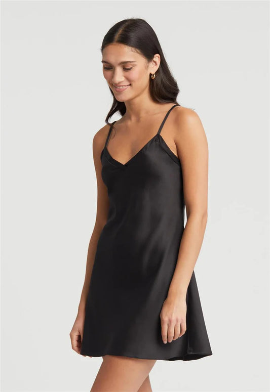 Woman wearing a black slip dress against a plain background