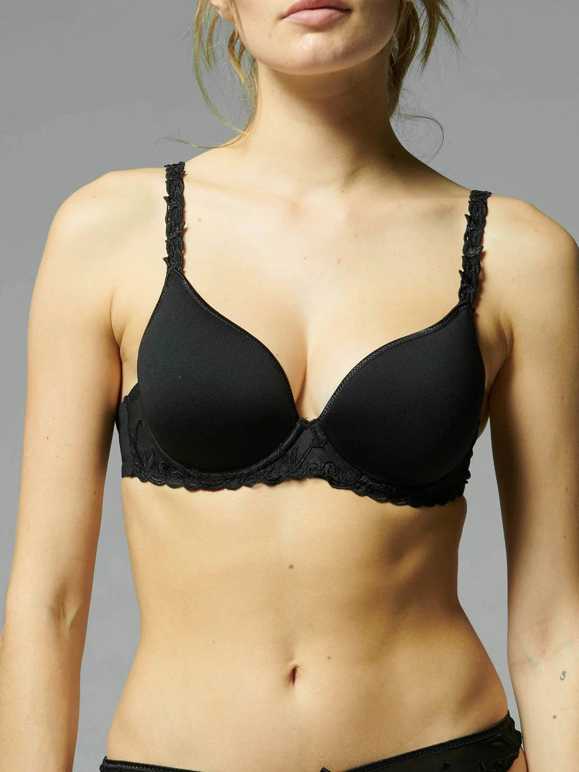 Black bra worn by a model against a gray background