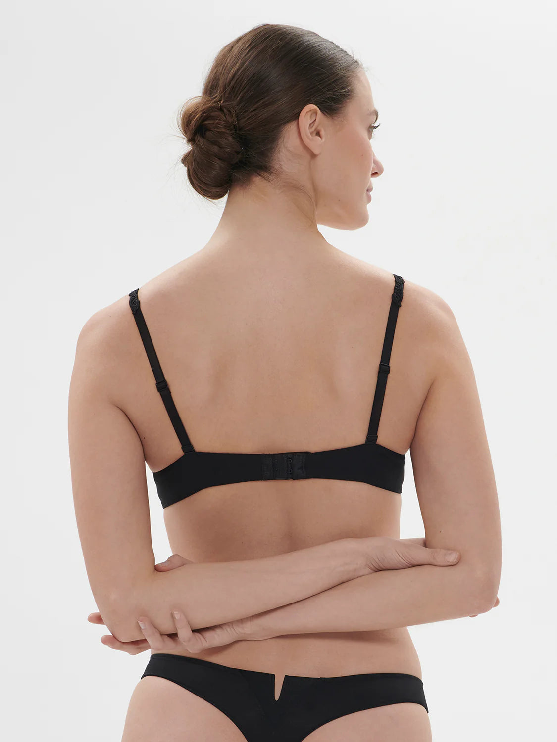 Woman wearing a black bra and underwear set on a white background