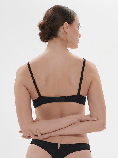 Woman wearing a black bra and underwear set on a white background