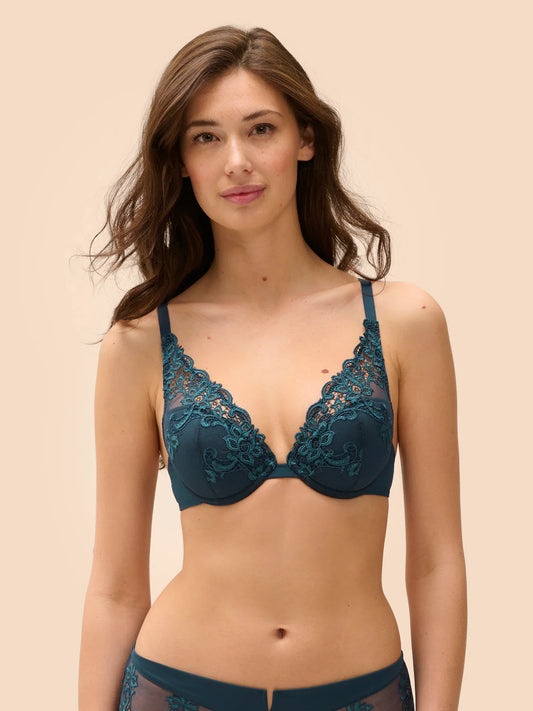 Woman wearing a teal lace bra and panties set on a beige background