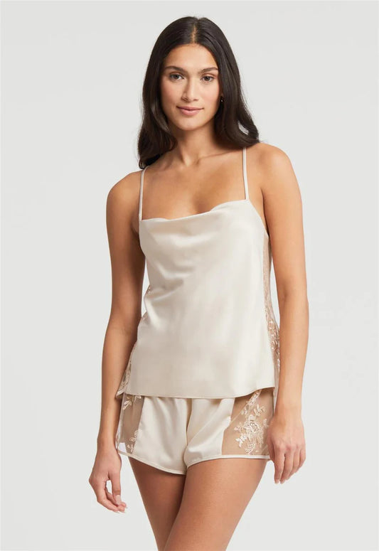 Woman wearing a cream satin camisole and shorts set on a plain background