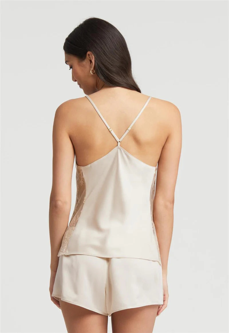 Woman wearing a beige satin top and shorts set on a plain background