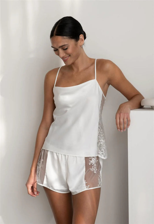 Woman wearing a white satin nightgown with sheer panels against a plain background