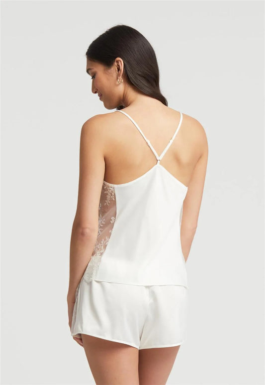 Woman wearing a white lace camisole and shorts set on a plain background