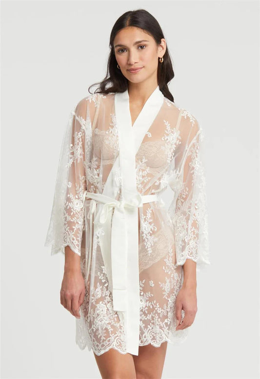 Woman wearing a white lace robe against a plain background
