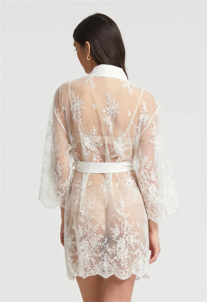 Woman wearing a sheer lace robe with a white belt on a light gray background