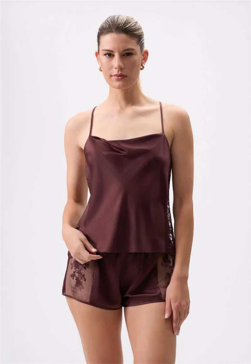 Woman wearing a brown satin camisole and shorts set on a white background
