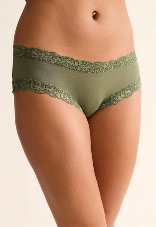 Green lace-trimmed underwear on a beige background
