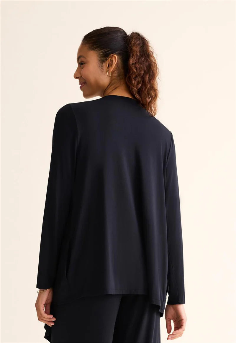 Woman wearing a black long-sleeve top against a beige background