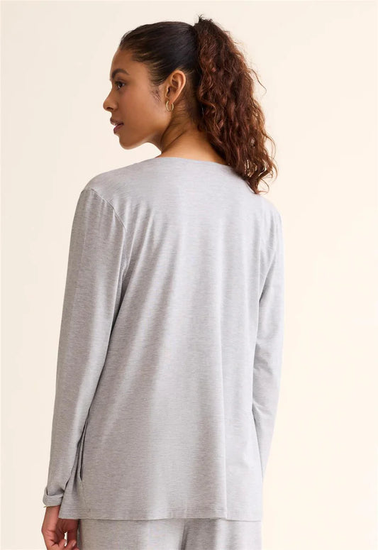 Woman wearing a light gray long-sleeve top against a beige background